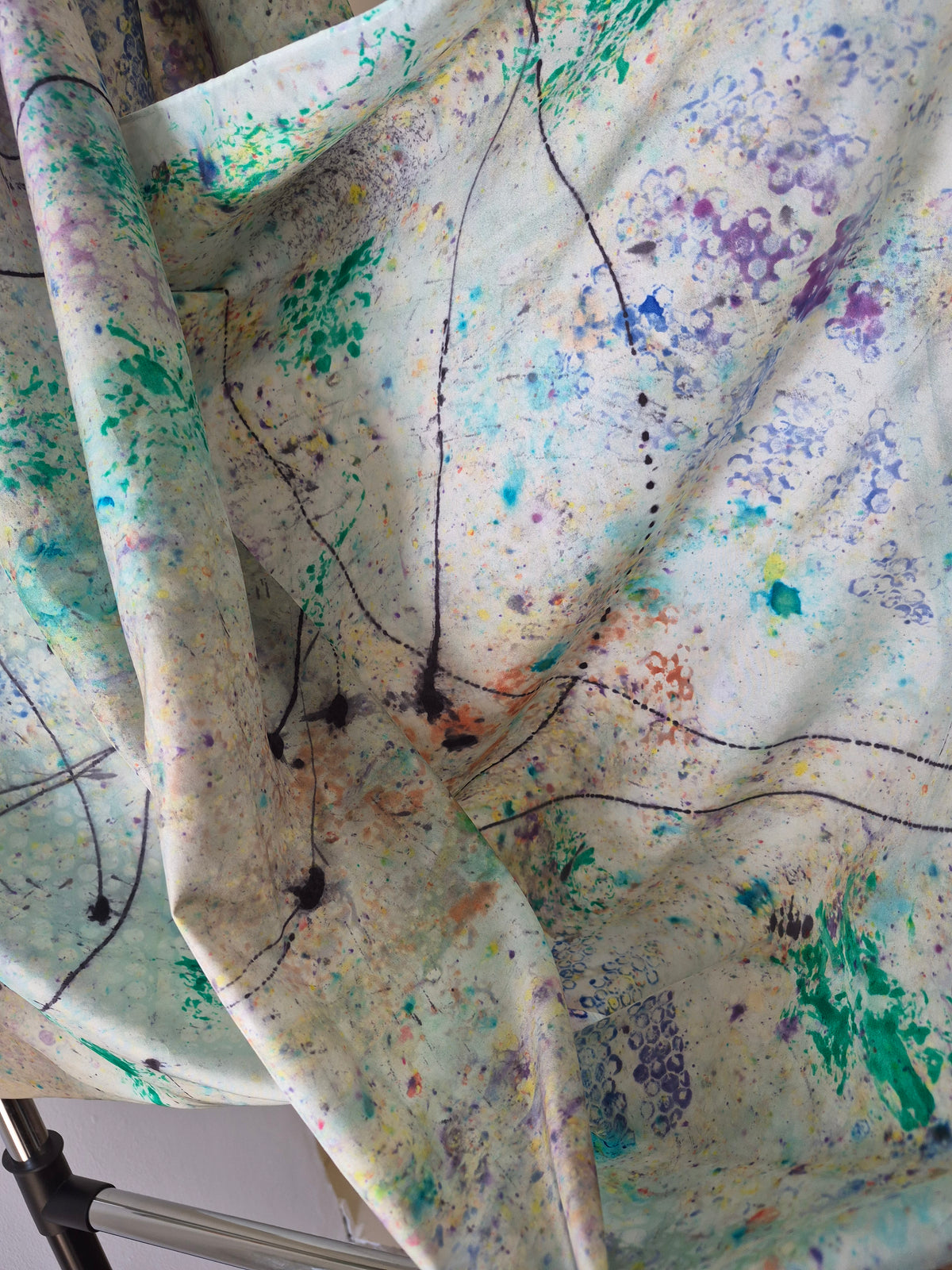Green Aphrodisiac hand-painted silk wrap, shown in a close-up with its abstract green, purple, blue, orange and black lines painted details