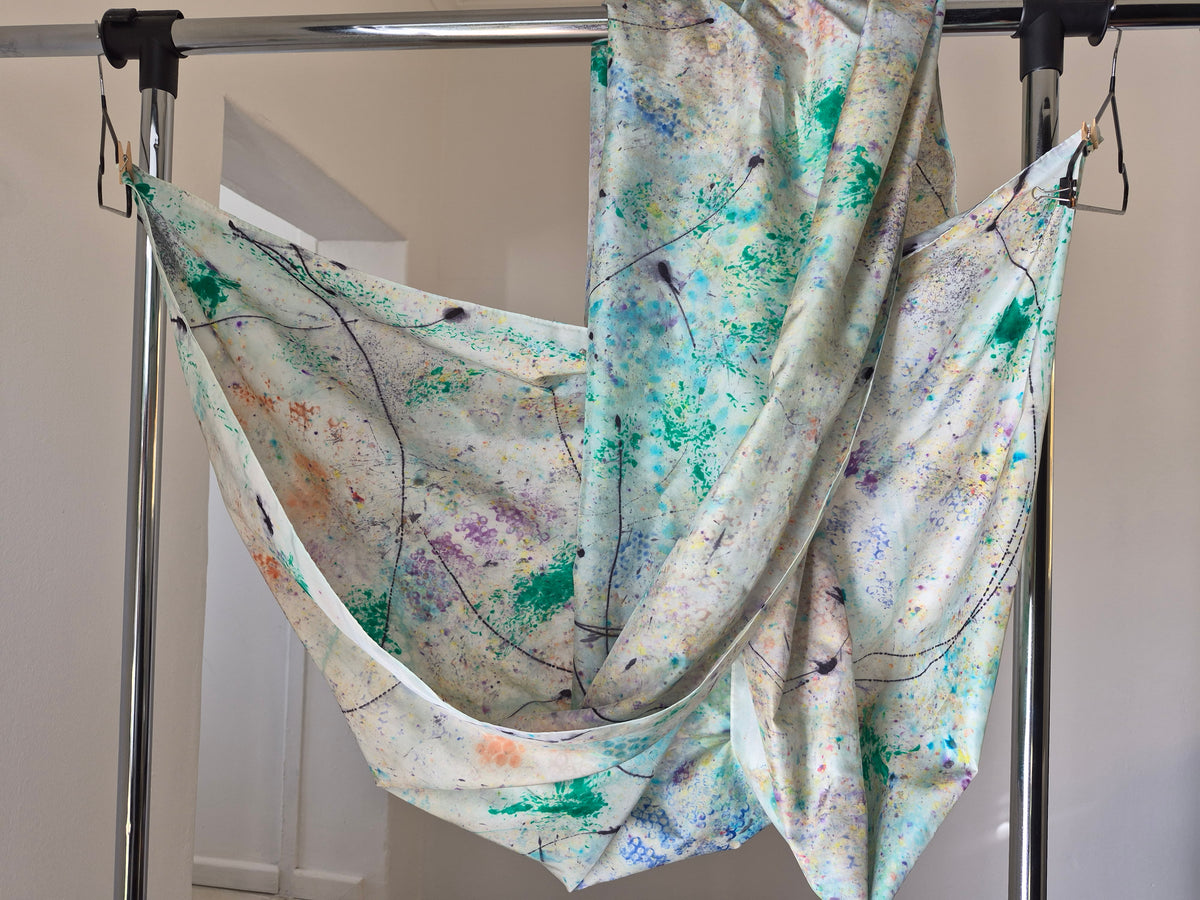 Green Aphrodisiac hand-painted silk wrap draped over a stand.