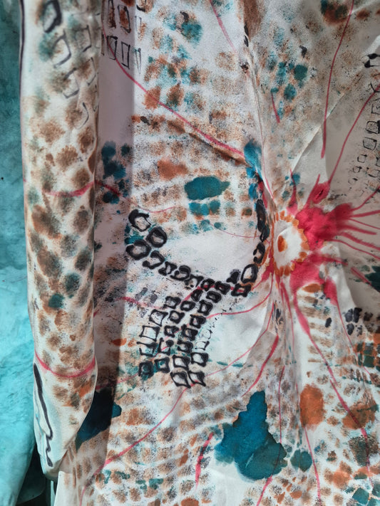 An up close of the Ode to Mum hand-painted Mulberry silk scarf featuring an abstract design in turquoise, coral, brown, black and red lines.